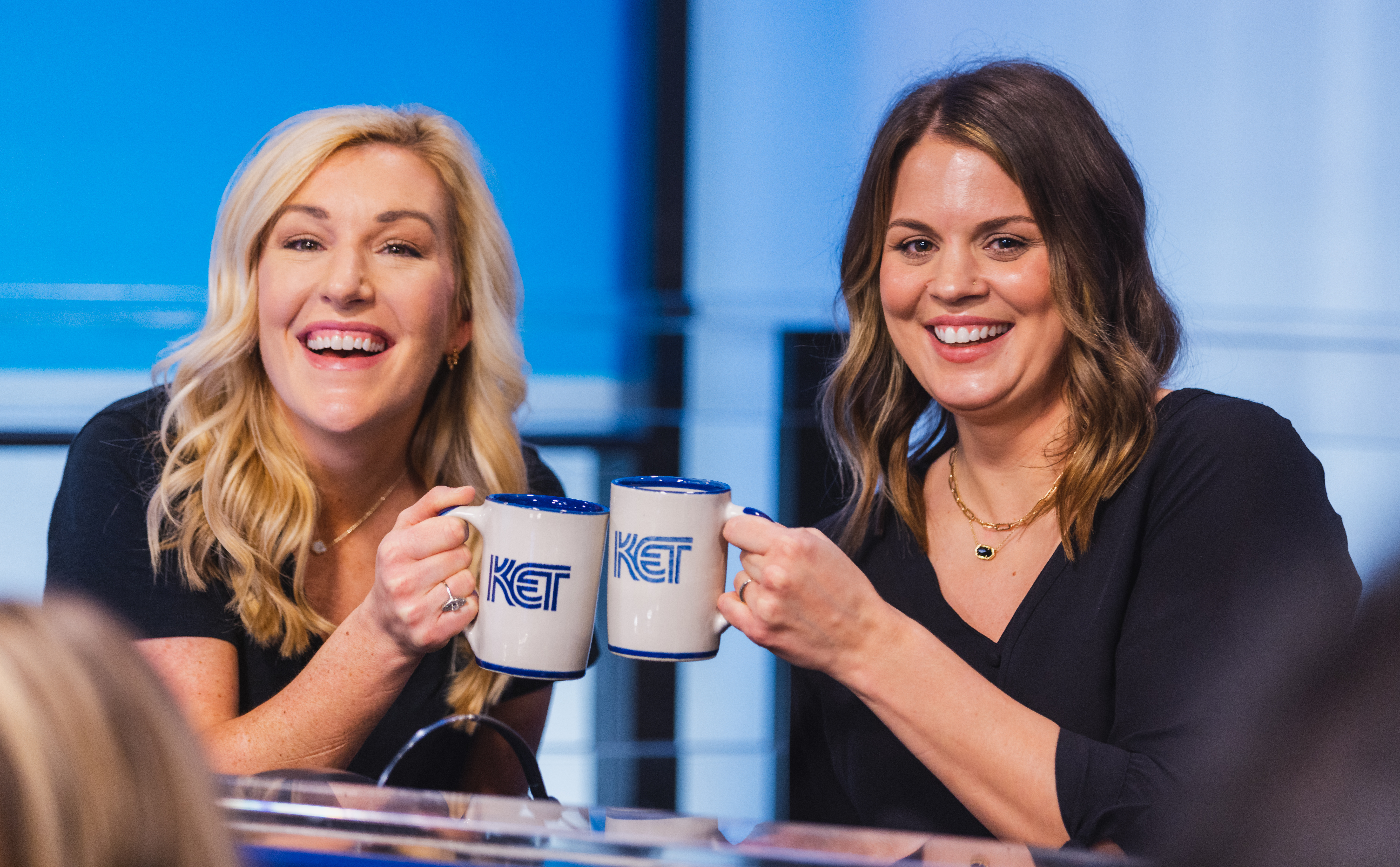 Two women holding KET mugs