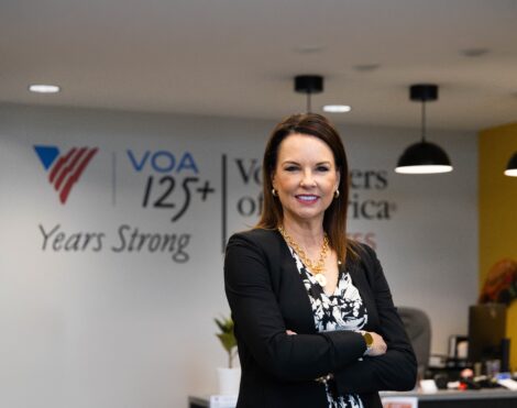 Jennifer Hancock arms crossed over her chest and smiling. Volunteers of America logo is on the wall behind her.